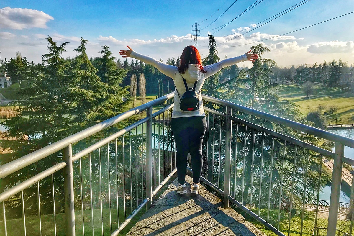 rear-view-woman-standing-footbridge-min