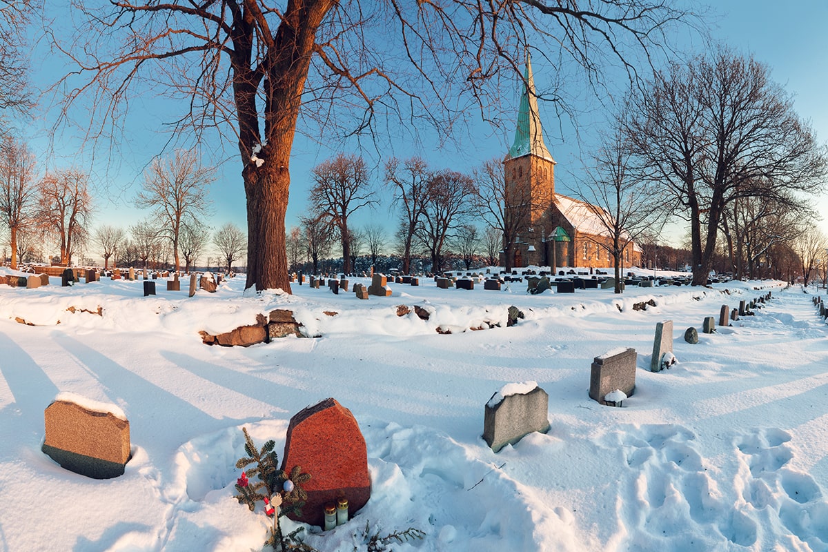 winter-landscape-with-norwegian-countryside-church-sunset-graveyard-foreground-min